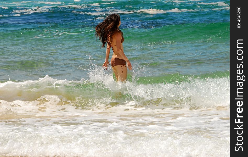 Young girl with hair blowing in the wind going for a swim in the ocean. Young girl with hair blowing in the wind going for a swim in the ocean