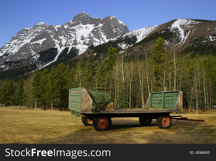 Hay wagon sitting at base of mountains in alberta canada. Hay wagon sitting at base of mountains in alberta canada
