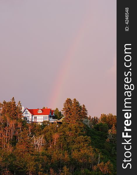 Rainbow over a red house in sunset, william hawrelak park, edmonton, alberta, canada. Rainbow over a red house in sunset, william hawrelak park, edmonton, alberta, canada