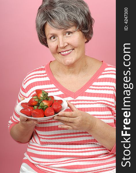 Portrait of a healthy senior woman with a bowl of strawberries. Portrait of a healthy senior woman with a bowl of strawberries