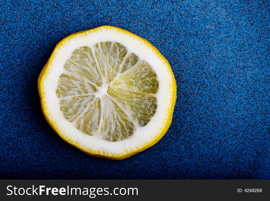 Image of a slice of lemon on a blue textured background. Image of a slice of lemon on a blue textured background