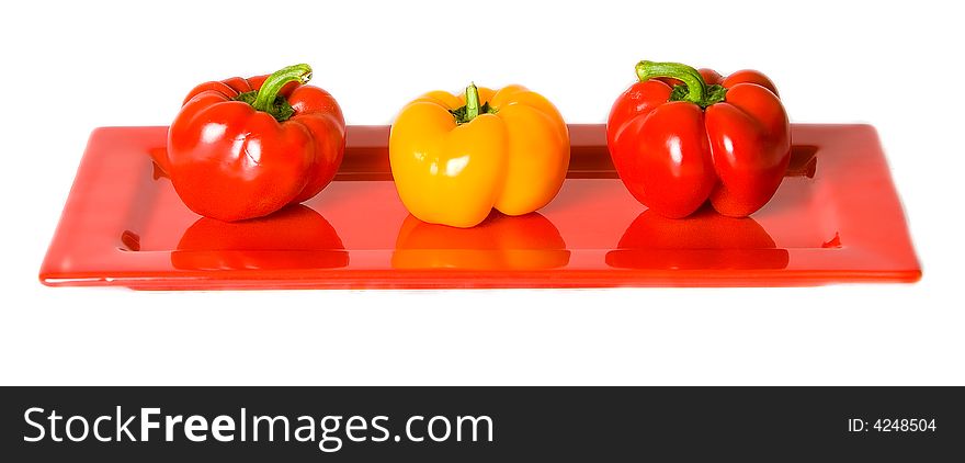 Three Bellpeppers Arranged On A Red Plate.