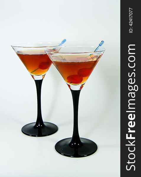 Two cocktails with cherry in front of white background