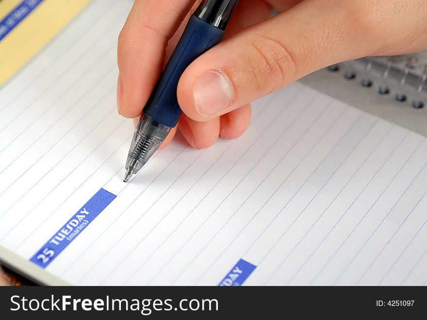 Close up of a hand writing in a daily planner