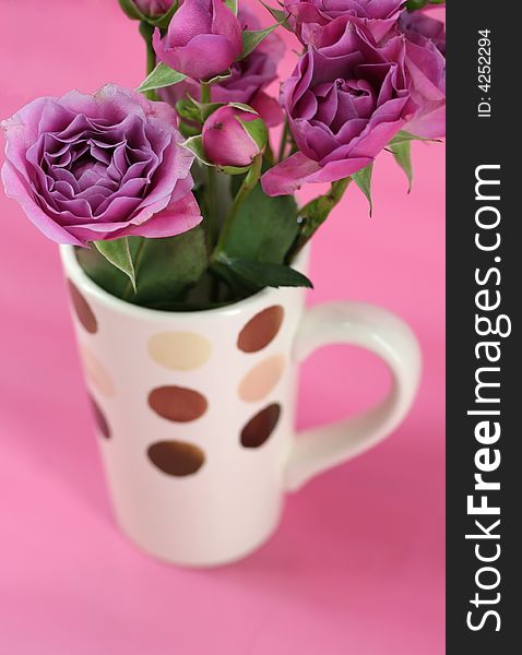 A bouquet of pink roses in a coffee mug. A bouquet of pink roses in a coffee mug