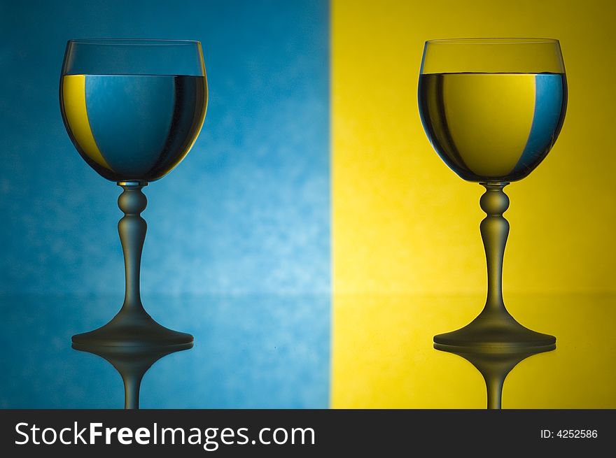 Glasses of water on the background divided by yellow and blue colour. Glasses of water on the background divided by yellow and blue colour