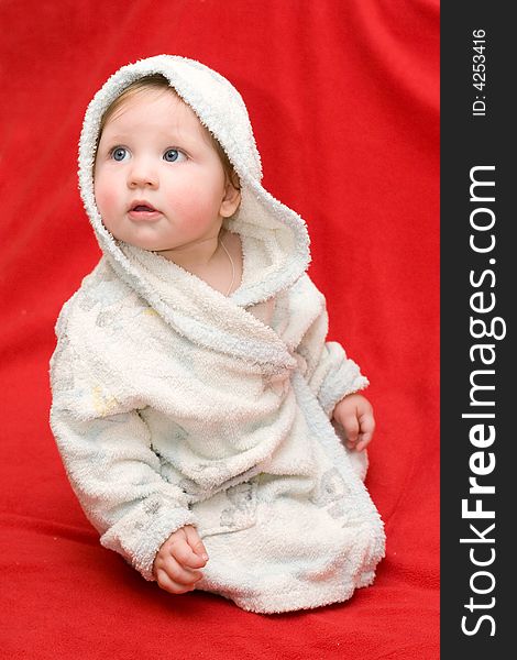 Baby in a white dressing-gown on a red background