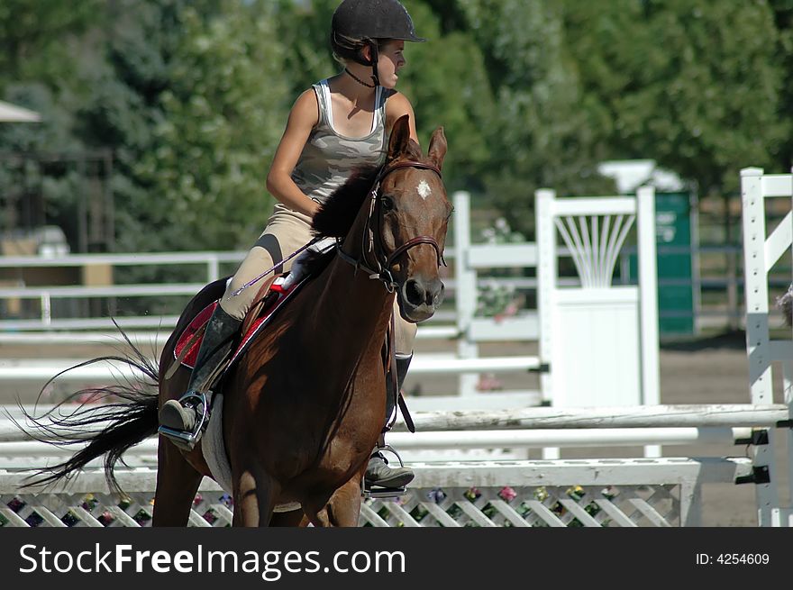 Teen girl  riding  thoroughbred in arena over jumps. Teen girl  riding  thoroughbred in arena over jumps.