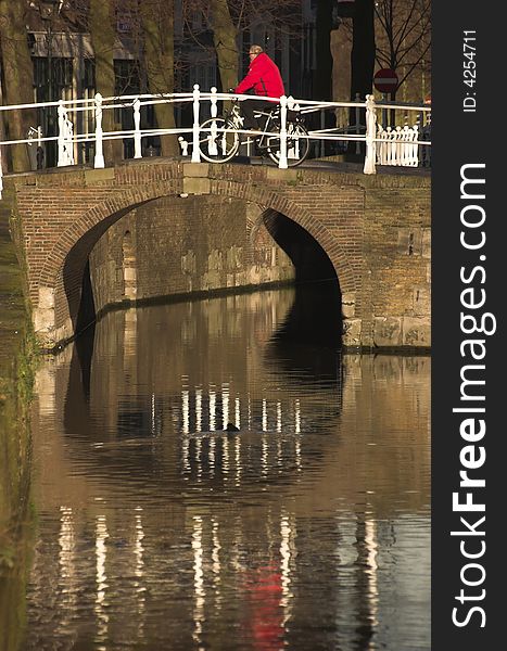 Pedestrian bridge in Delft being crossed by a cyclist wearing red jacket