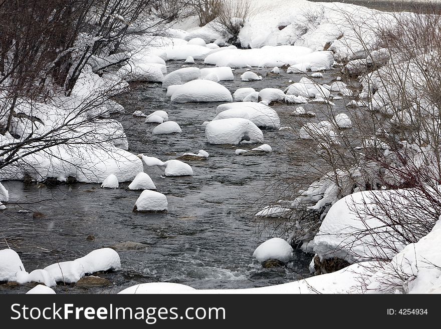 Snow-covered rocks in a river. Snow-covered rocks in a river.