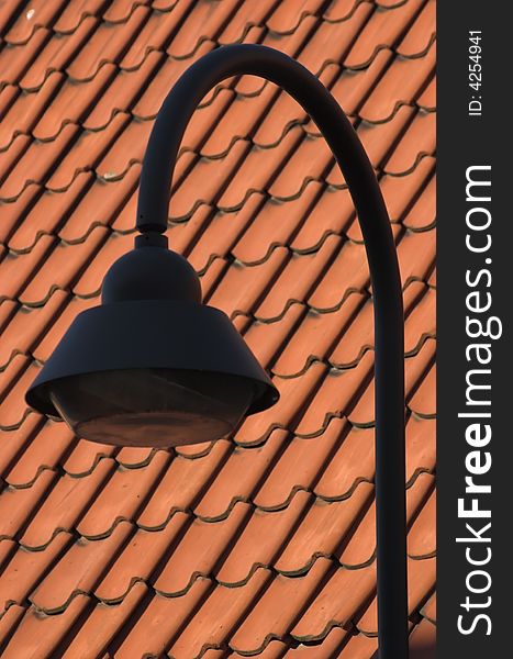Street lamp next to a red tiled roof