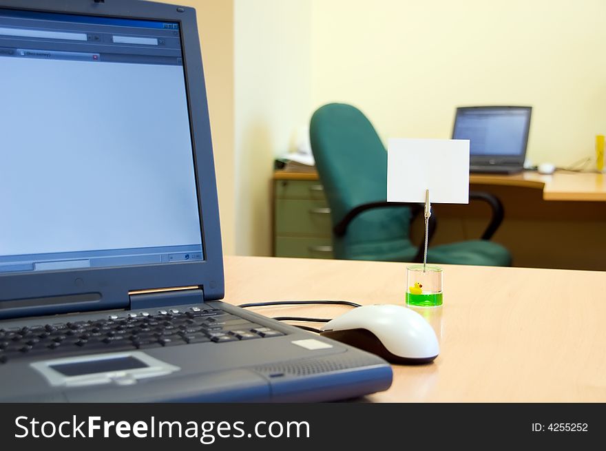 An empty open-plan office with a blank reminder note on the desk by a laptop computer. An empty open-plan office with a blank reminder note on the desk by a laptop computer.