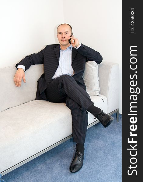Businessman with mobile phone sitting at sofa