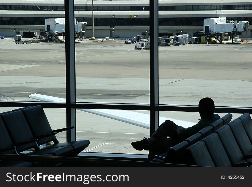 Silhouette of sitting man waiting at the airport, looking out at the runway. Silhouette of sitting man waiting at the airport, looking out at the runway.