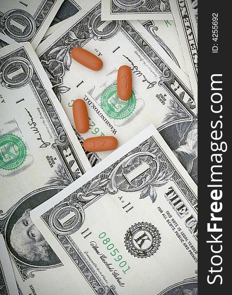 Pills on us currency. Concept of medicating an injured economy, or concept of the cost of medication. Pills on us currency. Concept of medicating an injured economy, or concept of the cost of medication