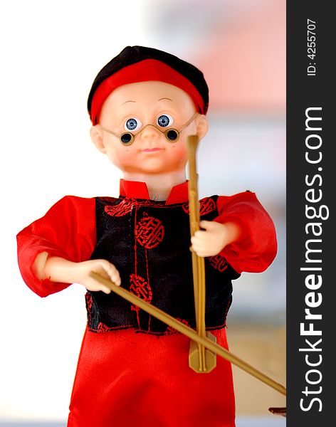 The doll of a chinese boy in traditional clothes,mandarin jacket and gown,playing urheenã€‚