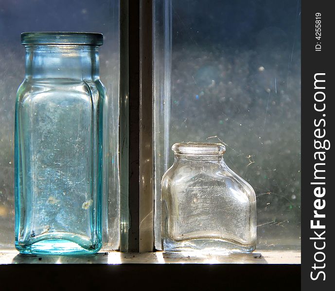 Two old medicine bottles lit by the sun.