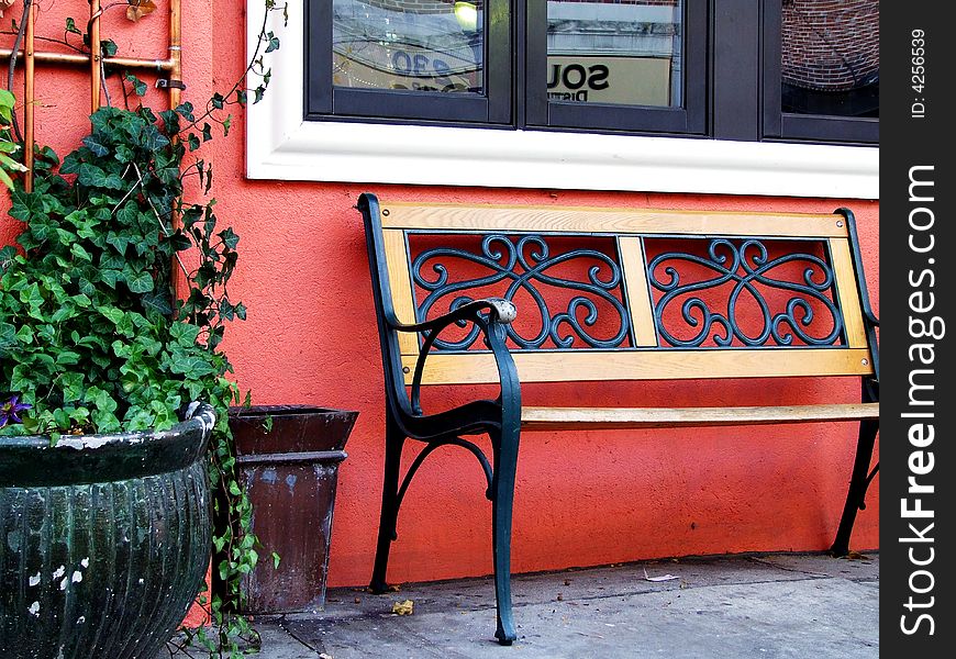 A bench on a sidewalk in front of a cafe. beautiful color. A bench on a sidewalk in front of a cafe. beautiful color.