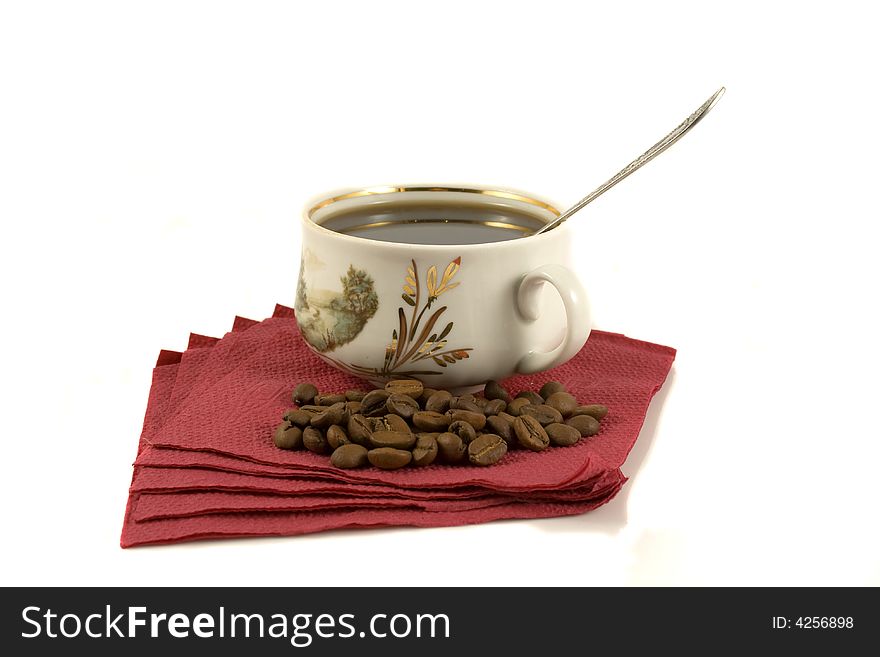 A cup of hot coffee on a red napkin with some coffee-beans. A cup of hot coffee on a red napkin with some coffee-beans