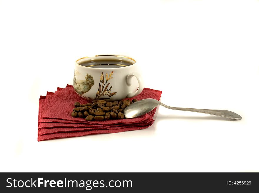 An isolated cup of hot coffee on a red napkin with some coffee-beans. An isolated cup of hot coffee on a red napkin with some coffee-beans