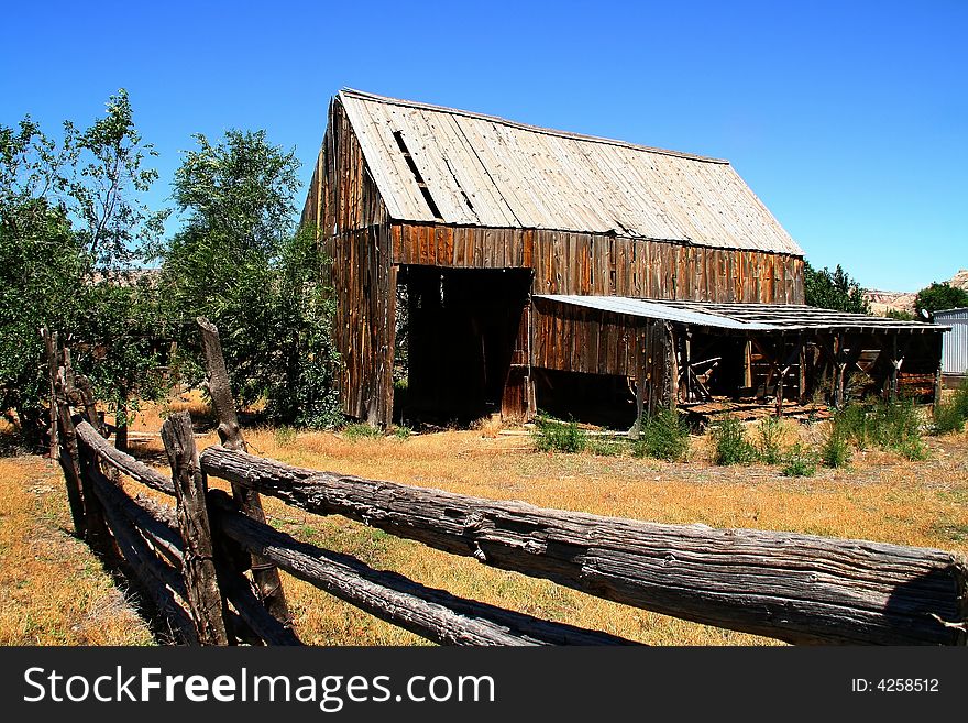 View of a hay barn eit a wood fense in the forground. View of a hay barn eit a wood fense in the forground