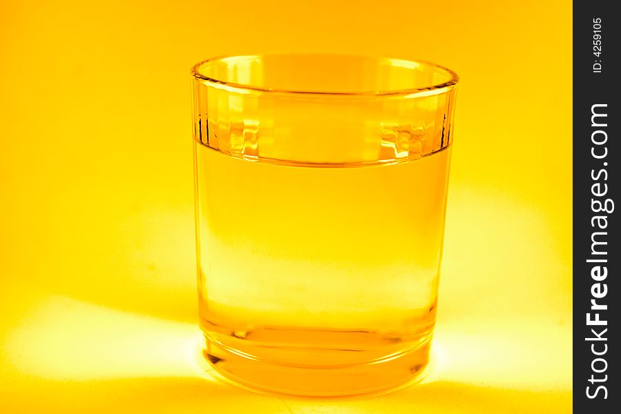 Single glass of water in orange background macro. Single glass of water in orange background macro