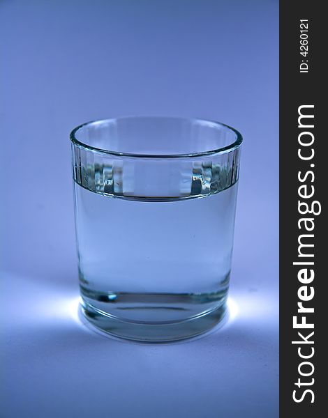 Single glass of water in blue colur macro