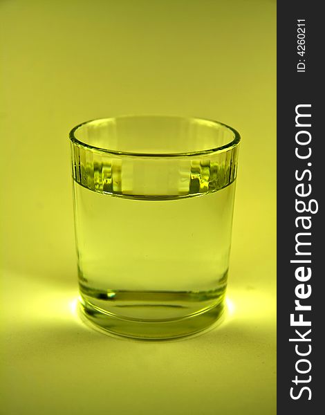 Single glass of water in yellow-green  colour macro