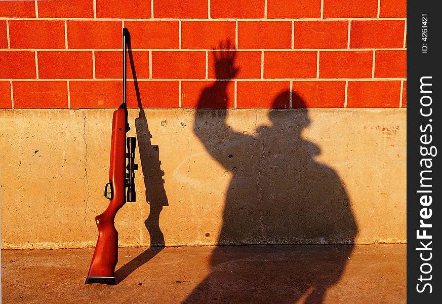 A rifle on the wall and a man's shadow. This versatile picture can be interpreted in many ways, with a lot of meanings. A rifle on the wall and a man's shadow. This versatile picture can be interpreted in many ways, with a lot of meanings