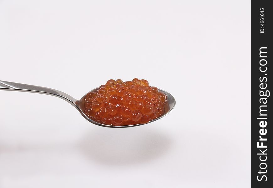 The spoon with red caviar on a white background