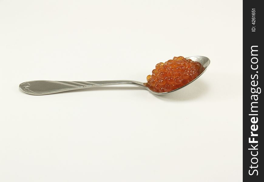 The spoon with red caviar on a white background