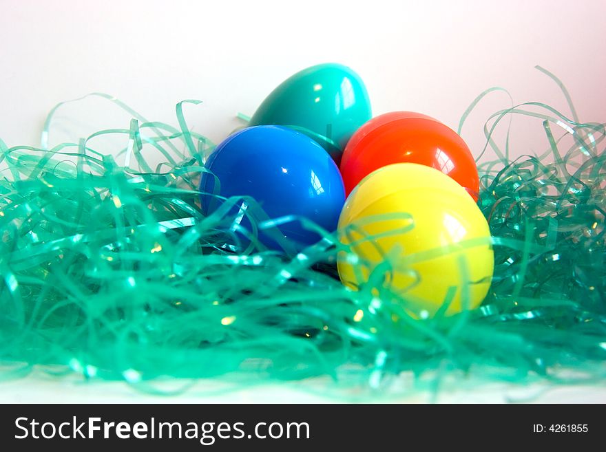 Yellow, blue, red and green plastic Easter Eggs in green plastic grass, isolated on white