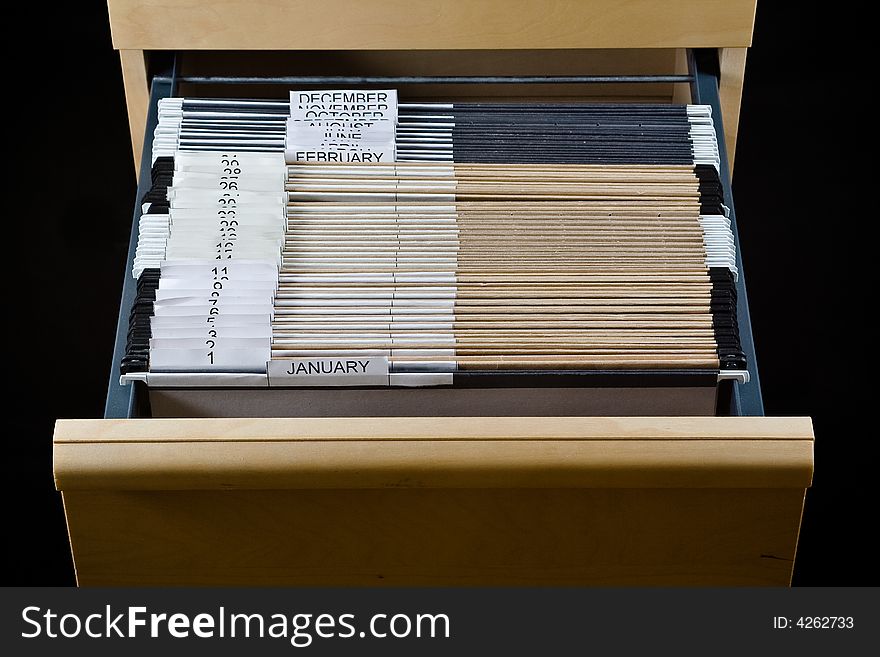 Wooden rolling file cabinet with a drawer opened, showing 43 hanging folders. Wooden rolling file cabinet with a drawer opened, showing 43 hanging folders.