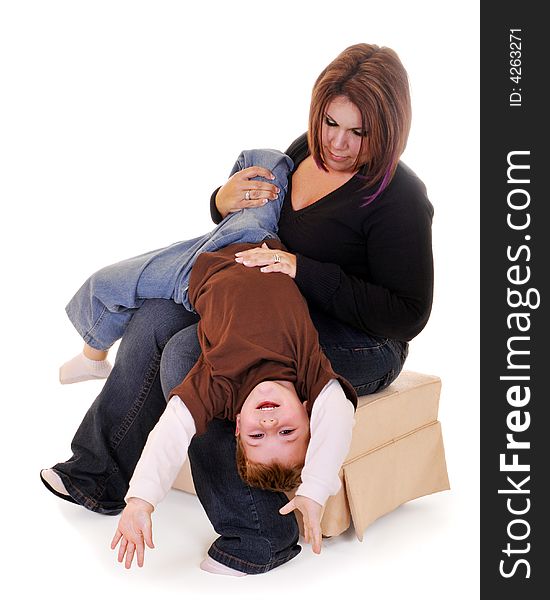 Preschool boy hanging upside down from his mom's lap. Isolated on white. Preschool boy hanging upside down from his mom's lap. Isolated on white.