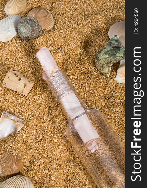 Rolled message in bottle with cork on sand, surrounded by sea shells. Rolled message in bottle with cork on sand, surrounded by sea shells.