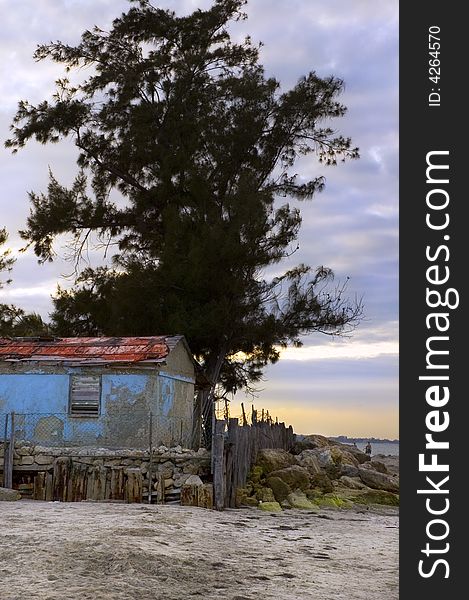 Beach scene with rustic cabin at sunset. Beach scene with rustic cabin at sunset