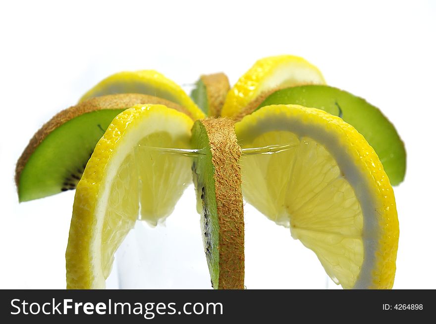 Parts of lemon and kiwi in the glass on white background. Parts of lemon and kiwi in the glass on white background