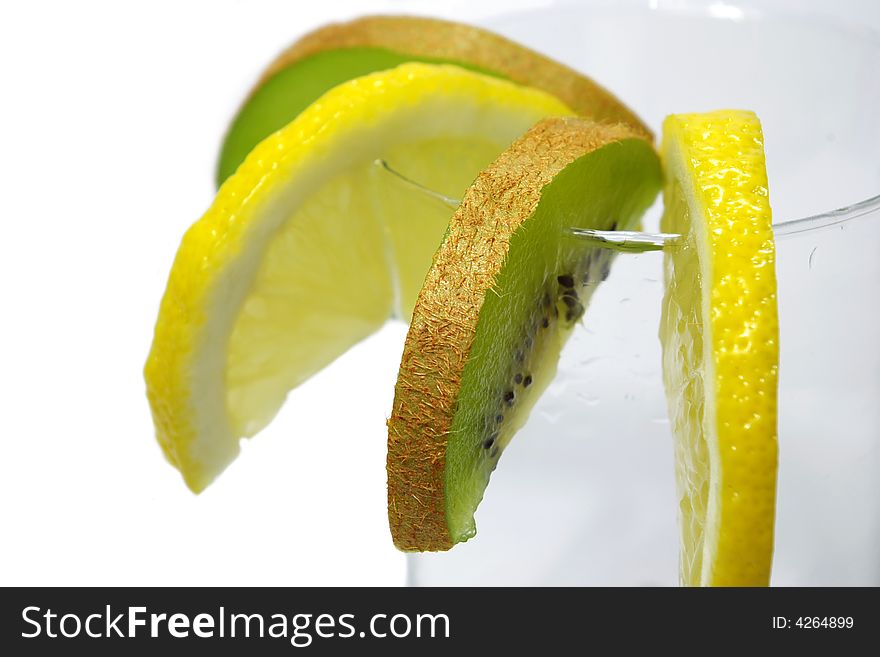 Parts of lemon and kiwi in the glass on white background. Parts of lemon and kiwi in the glass on white background