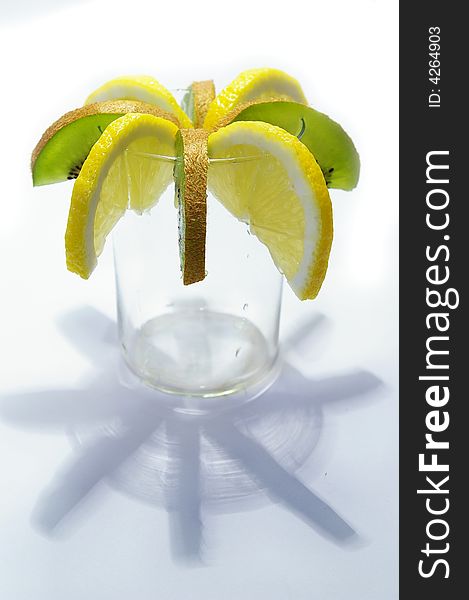 Parts of lemon and kiwi in the glass on white background