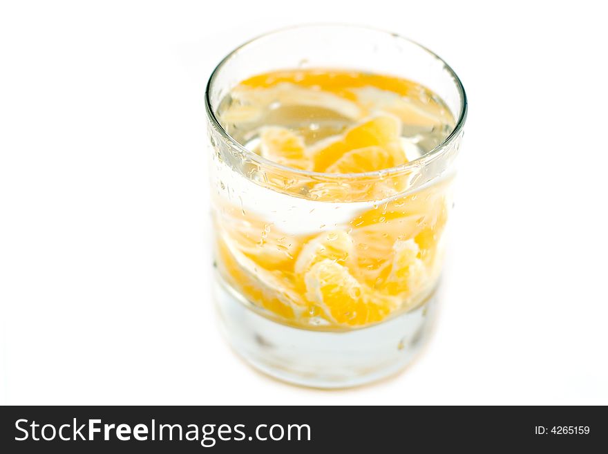 Lobules of mandarine at glass water isolated on white