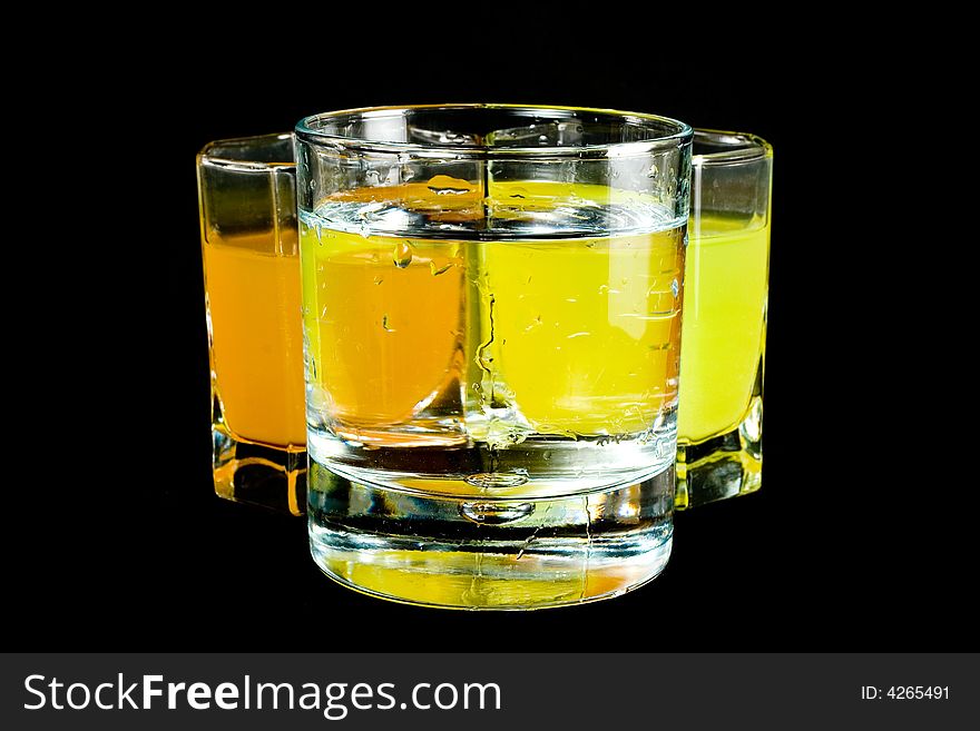 Three glasses with colored liquid isolated on black background
