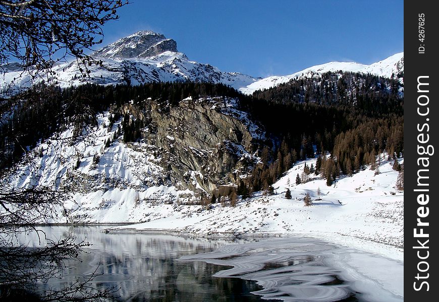 The partly frozen Marmorera Reservoir - besides the road to the Julier Pass - and Mount Piz Ela, 3339 m / 10955 ft., eastern Switzerland. The former village of Marmorera became a victim of the reservoir and then was built in a higher place.