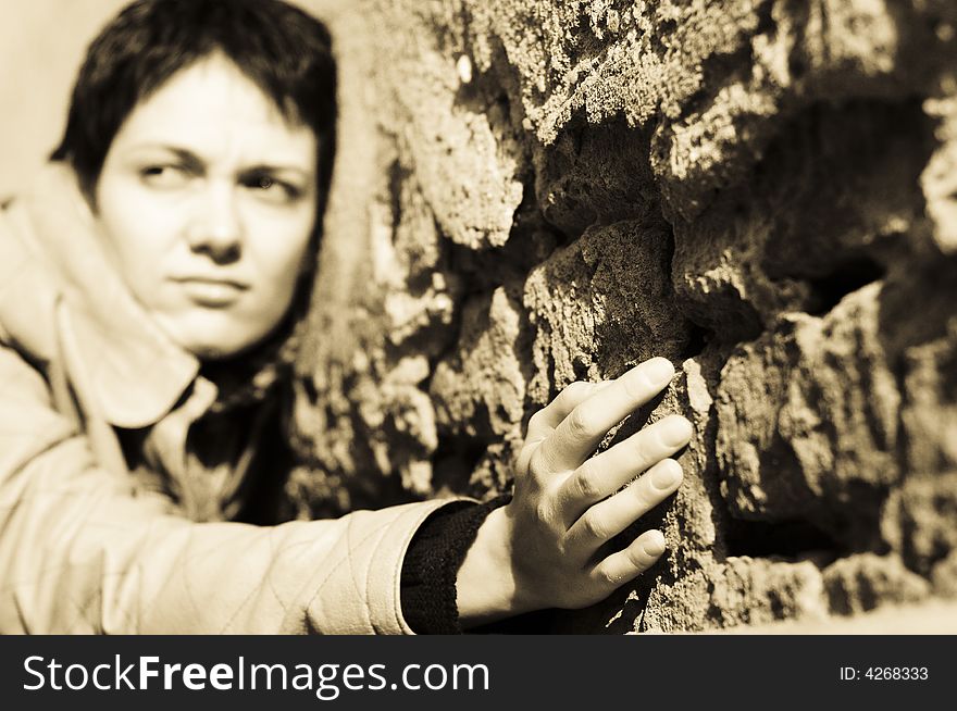 A view with a woman looking thoughtful in sepia tones. Shallow depth of field, focus on the hand.
