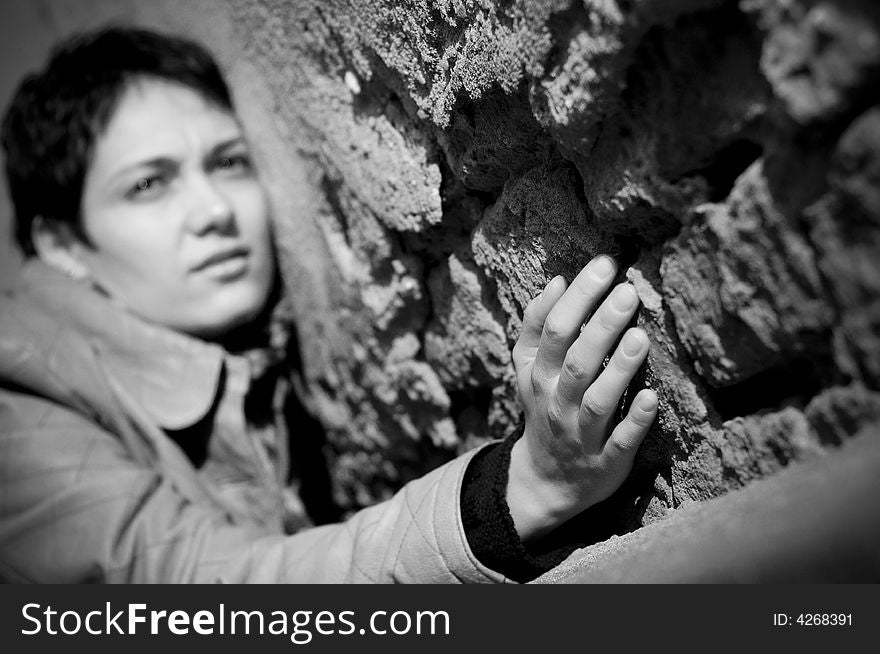 A view with a woman looking thoughtful in black and white tones. Shallow depth of field, focus on the hand.