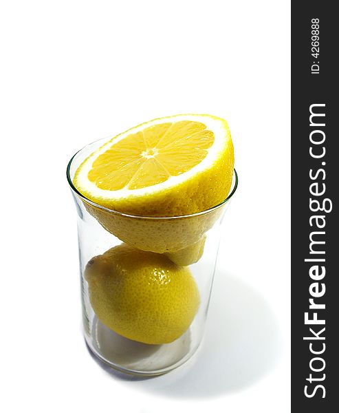 Two parts of yellow ripe lemon in the glass on white background. Two parts of yellow ripe lemon in the glass on white background