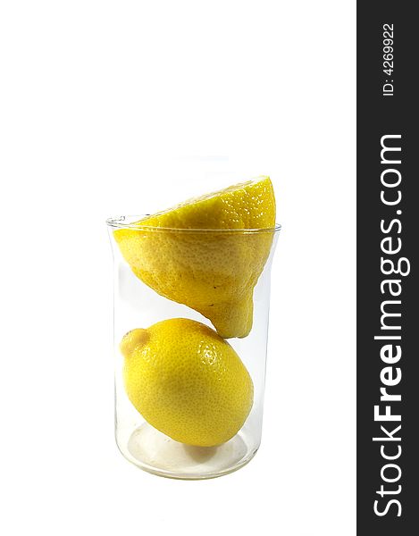 Two parts of yellow ripe lemon in the glass on white background