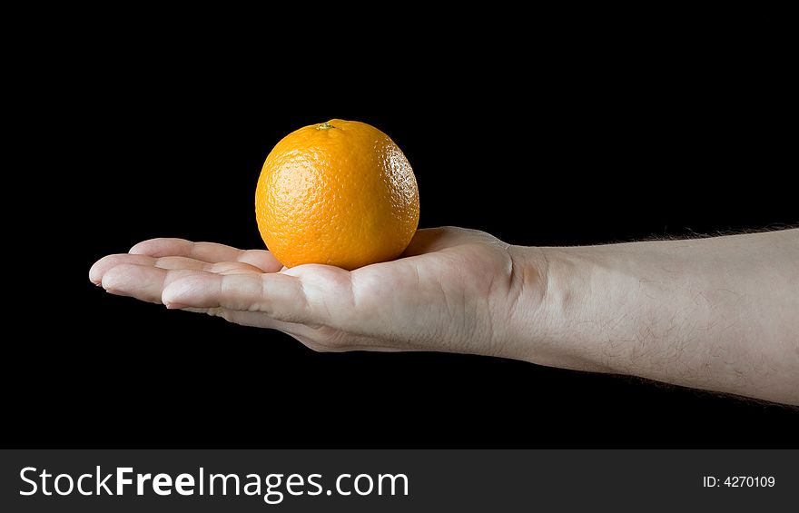 Orange on the palm. Isolated on a black background.