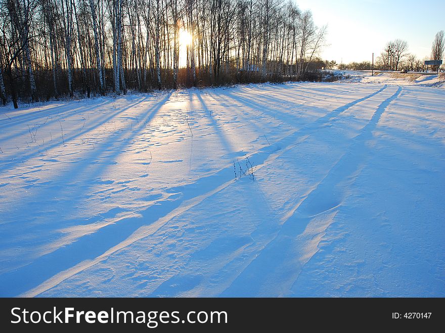 Sunset in winter rural; shadows of trees are cross the old road. Sunset in winter rural; shadows of trees are cross the old road