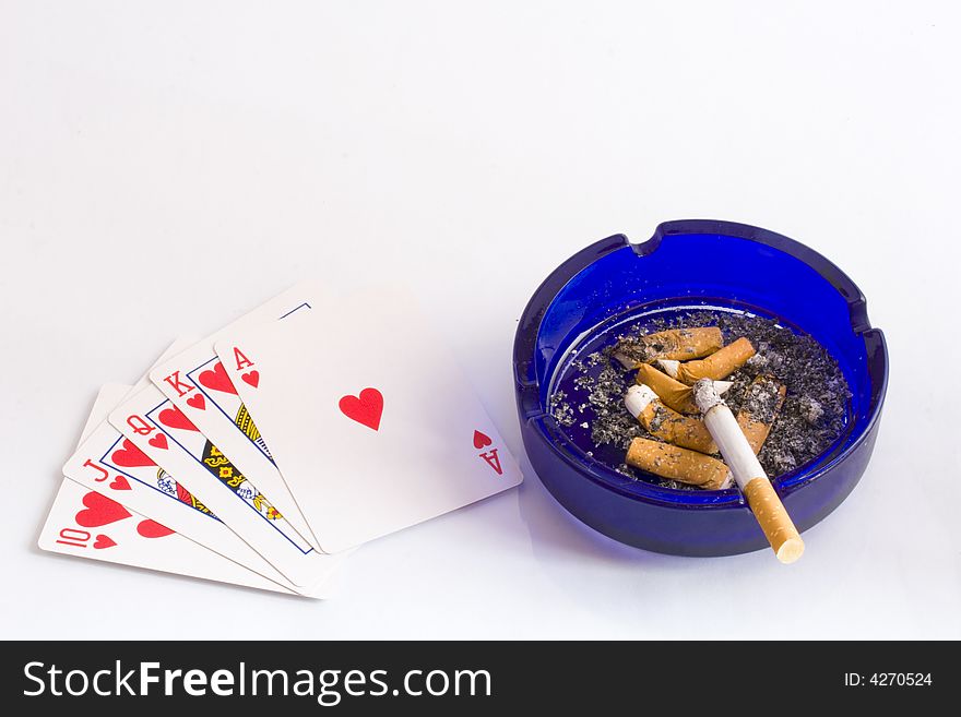 Cigarettes in an ashtray alongside playing cards. Cigarettes in an ashtray alongside playing cards