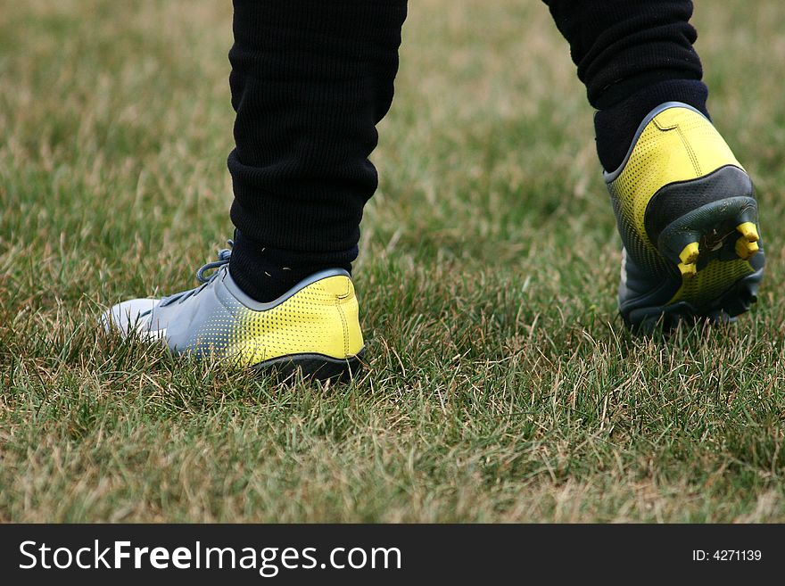 Grey and yellow soccer shoes on grass